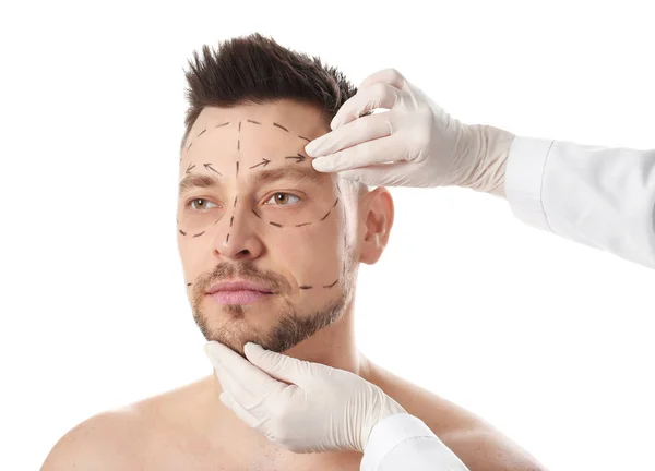 Доктор вивчає обличчя людини перед операцією пластичної хірургії на білому тлі — стокове фото