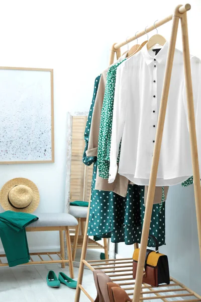 Cremalheira de guarda-roupa com roupas femininas e sapatos na parede de cor no quarto — Fotografia de Stock