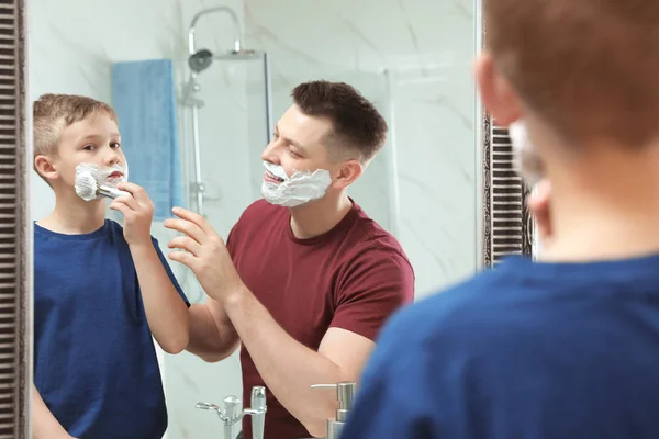Papa leert zijn zoon om scheerschuim op het gezicht in spiegel te brengen — Stockfoto