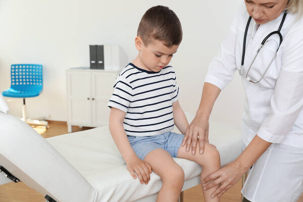 Врач осматривает маленького пациента с проблемами с коленом в клинике
