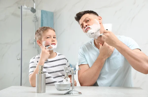 Папа бреется, а сын подражает ему в ванной. — стоковое фото
