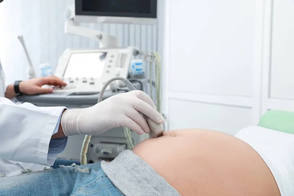 Νεαρή έγκυος γυναίκα που υποβάλλεται σε υπερηχογράφημα στη σύγχρονη κλινική, θέα στο κοντινό πλάνο — Φωτογραφία Αρχείου