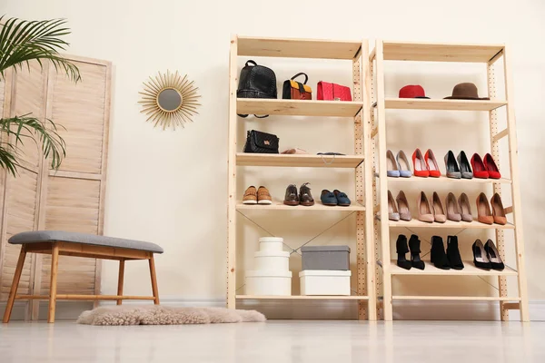 Houten rekken eenheid met verschillende schoenen en accessoires in stijlvolle kamer interieur — Stockfoto