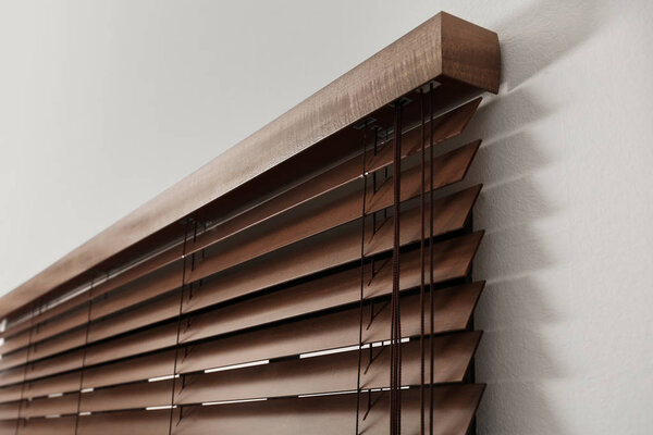 Modern window with closed stylish wooden blinds indoors, closeup view