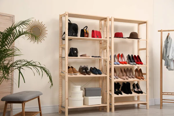 Деревянные стеллажи с различной обувью и аксессуарами в стильном интерьере комнаты — стоковое фото