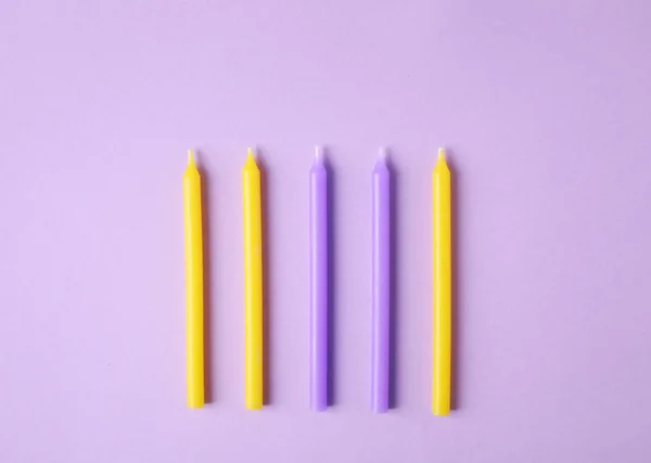 Velas de aniversário coloridas em fundo lilás, flat lay — Fotografia de Stock