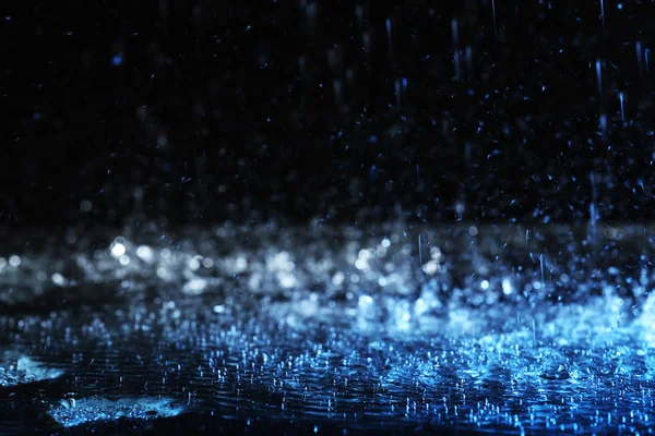 Проливной дождь падает на землю на темном фоне, тонированный в синий цвет — стоковое фото