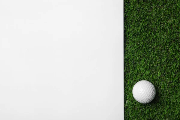 Bola de golfe e papel branco na grama artificial verde, vista superior com espaço para texto — Fotografia de Stock