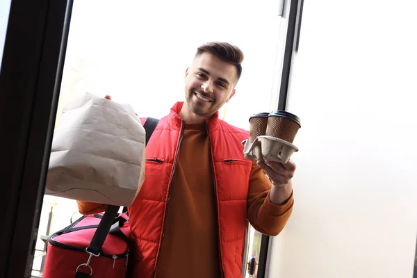 Portrait of courier with order at open door. Food delivery service — Stock Photo, Image