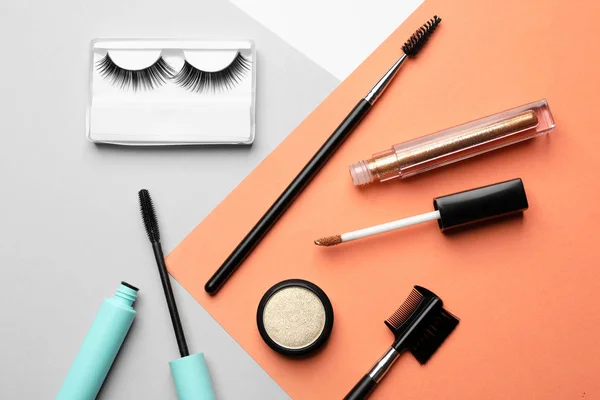 Composición plana con pestañas postizas y otros productos de maquillaje sobre fondo de color — Foto de Stock