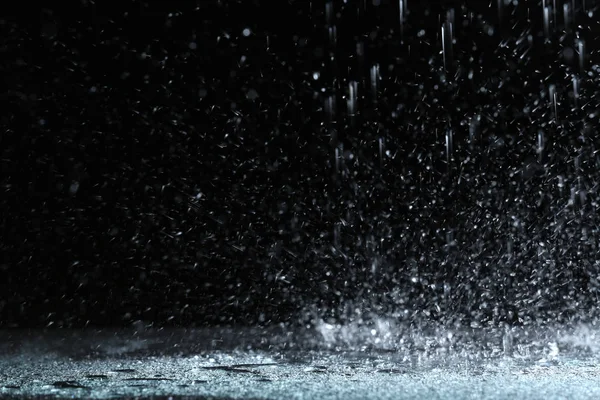 Hujan lebat jatuh di tanah terhadap latar belakang gelap — Stok Foto
