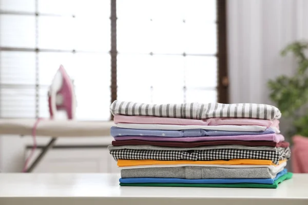 Ropa limpia plegada en la mesa en el interior, espacio para el texto. Día de lavandería — Foto de Stock