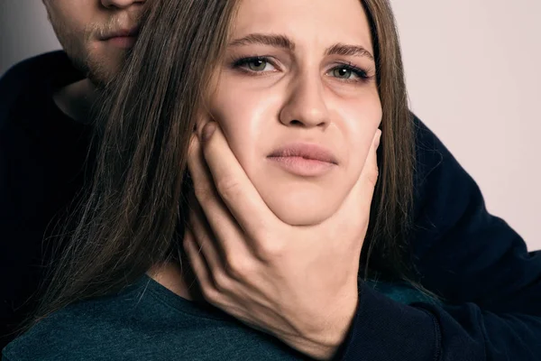 Hombre abusando de mujer joven en fondo claro. Detener la agresión sexual — Foto de Stock