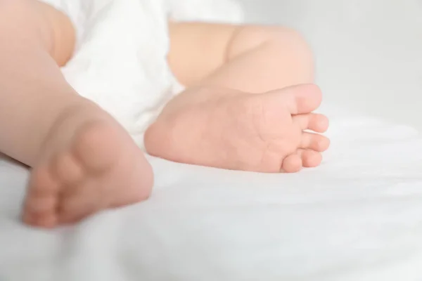 Kleines Baby mit niedlichen Füßen auf Bettlaken, Nahaufnahme — Stockfoto