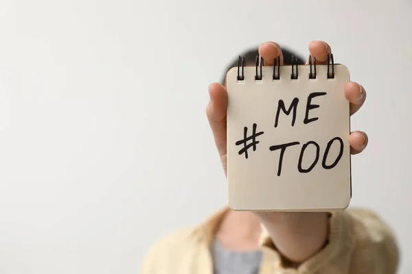 Vrouw houder notebook met hashtag metoo tegen lichte achtergrond, close-up. Stop seksueel geweld — Stockfoto