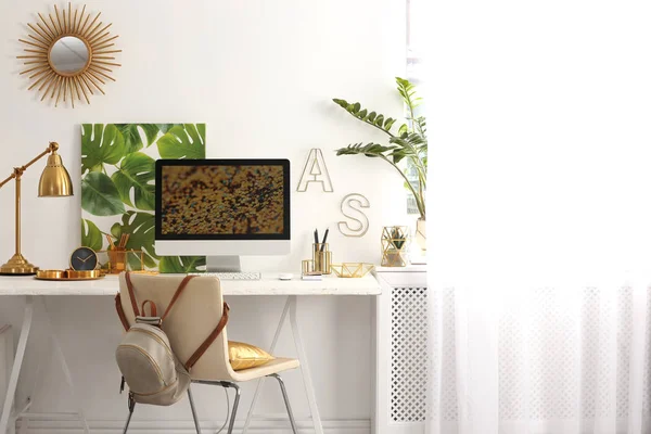 Duvara yakın masada bilgisayar ve altın dekora sahip modern işyeri. Şık iç tasarım — Stok fotoğraf