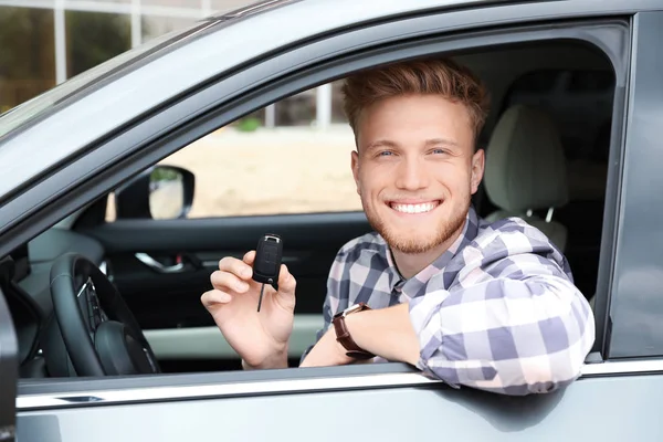 Jeune homme attrayant avec clé dans une voiture moderne — Photo