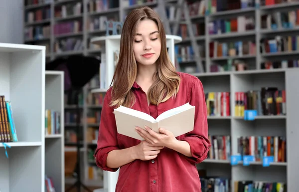 Jeune femme lisant un livre dans une bibliothèque moderne — Photo