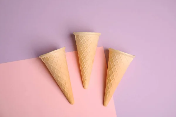 Conos de helado de oblea vacíos sobre fondo de color, posición plana — Foto de Stock