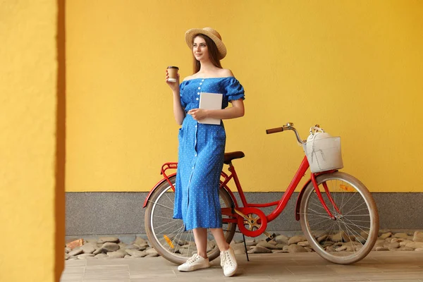Женщина с современным цветом велосипеда возле стены снаружи — стоковое фото