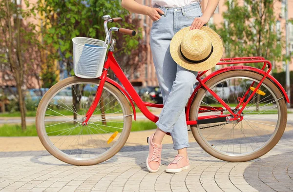 Mujer joven cerca de la bicicleta de color moderno en el exterior, primer plano — Foto de Stock