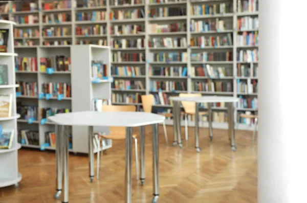 Vista turva de estantes e tabelas na biblioteca — Fotografia de Stock