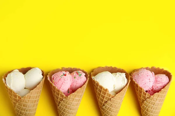 Deliciosos sorvetes em cones wafer no fundo amarelo, flat lay. Espaço para texto — Fotografia de Stock