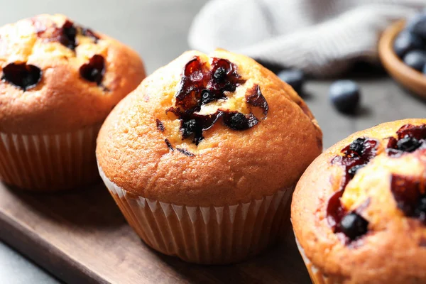 Tasty blueberry muffins on wooden board, closeup view — Stock Photo, Image