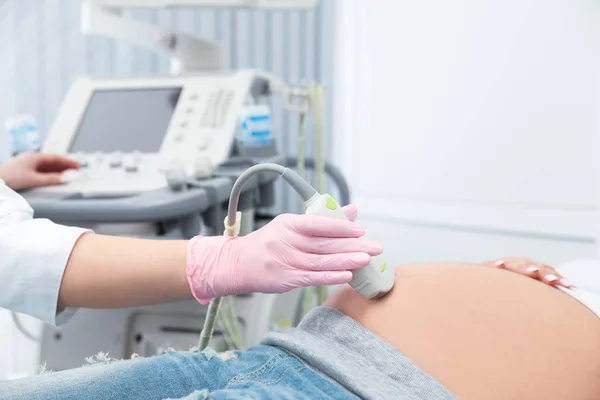 Young pregnant woman undergoing ultrasound scan in modern clinic — Stock Photo, Image
