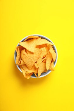 Sarı arka plan üzerinde kase lezzetli meksika nachos cips, üst görünümü