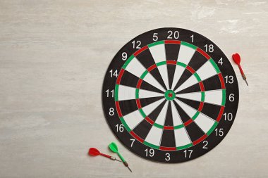 Hafif taş arka planda renk okları ile dart tahtası, üst görünüm. Metin alanı