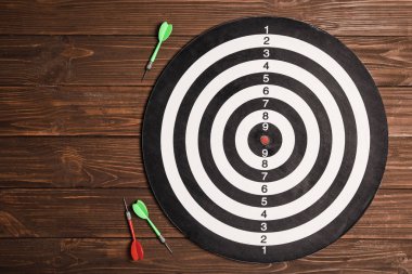 Ahşap arka plan üzerinde renk okları ile dart tahtası, üst görünüm. Metin alanı