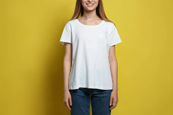 Ung kvinna klädd i blank t-shirt på gul bakgrund, närbild. Mockup för design — Stockfoto