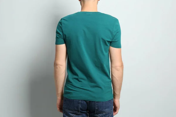 Vista posteriore del giovane che indossa t-shirt bianca su sfondo chiaro, primo piano. Mockup per il design — Foto Stock