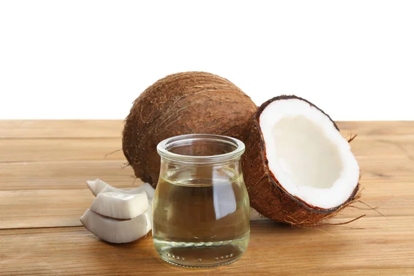 Cocos maduros y frasco con aceite orgánico natural sobre mesa de madera sobre fondo blanco — Foto de Stock