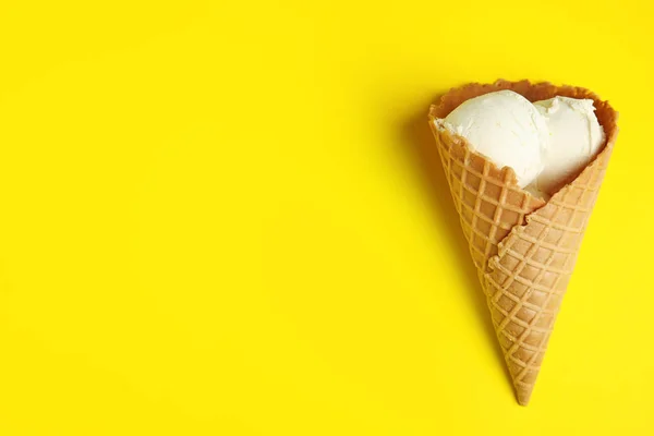 Pyszne lody waniliowe w stożek wafel na żółtym tle, widok z góry. Miejsce na tekst — Zdjęcie stockowe