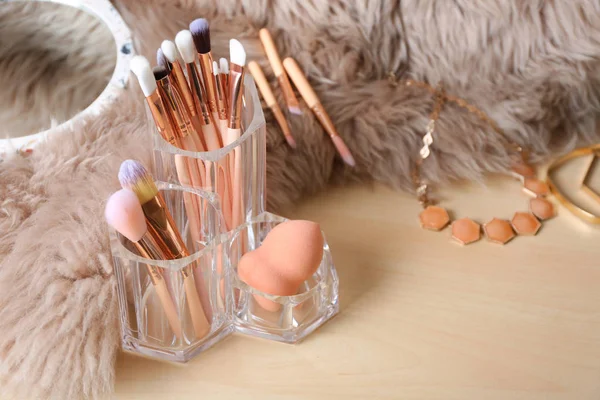 Organizer with set of professional makeup brushes and accessories on wooden table. Space for text