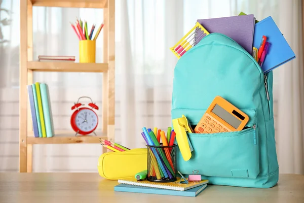 Mochila brillante y papelería escolar en la mesa en el interior, espacio para el texto —  Fotos de Stock