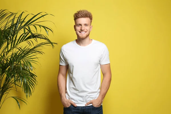 Young man wearing blank t-shirt on yellow background. Mockup for design — Stock Photo, Image