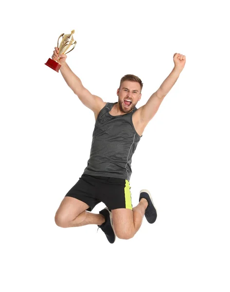 Excited young sportsman with gold trophy cup jumping on white background