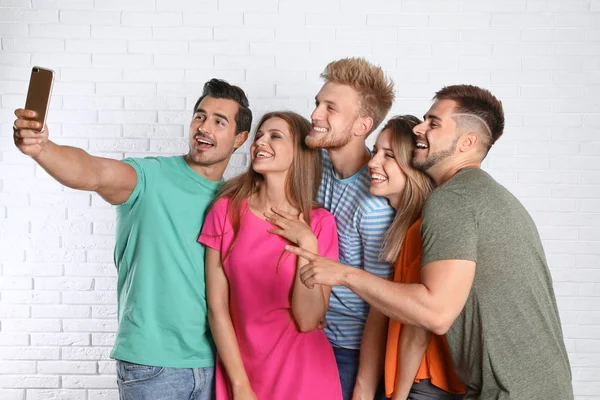 Jeunes gens heureux prenant selfie près du mur de briques blanches — Photo