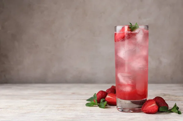 Vaso de refrescante bebida con fresa y menta sobre mesa de madera clara sobre fondo gris, espacio para texto —  Fotos de Stock