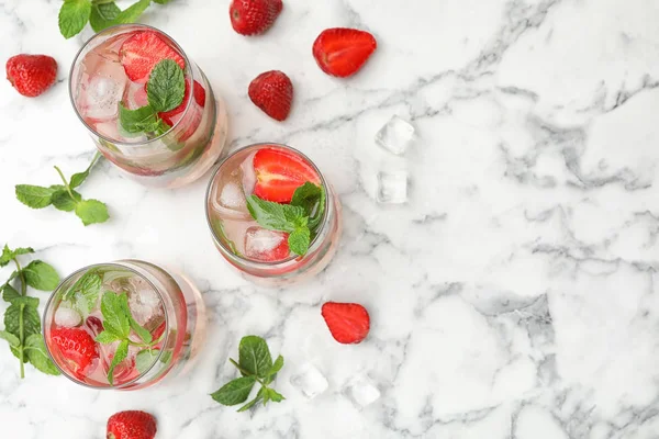 Vasos de bebida refrescante con fresa y menta en la mesa de mármol, la puesta plana. Espacio para texto —  Fotos de Stock