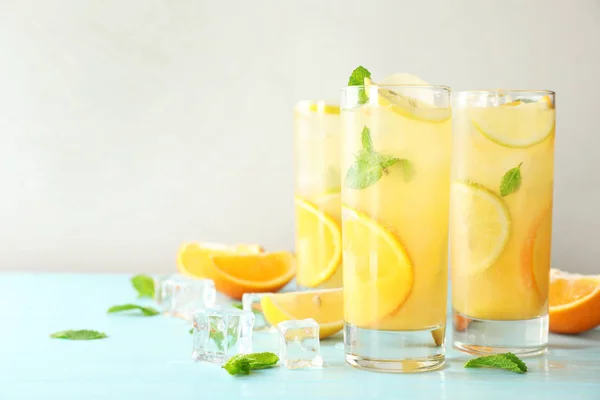 Brýle na osvěžení citrusových nápojů na světle modrém dřevěném stole, prostor pro text — Stock fotografie
