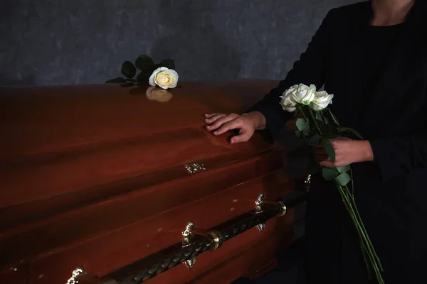 Young woman with white roses near casket in funeral home, closeup — Stock Photo, Image