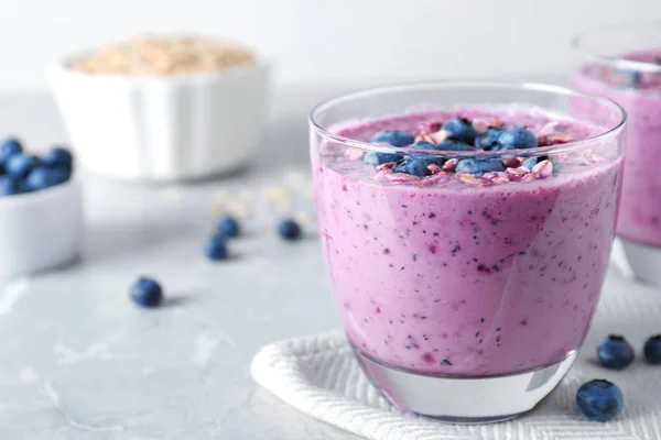 Vaso de sabroso batido de arándanos con muesli sobre mesa gris. Espacio para texto —  Fotos de Stock