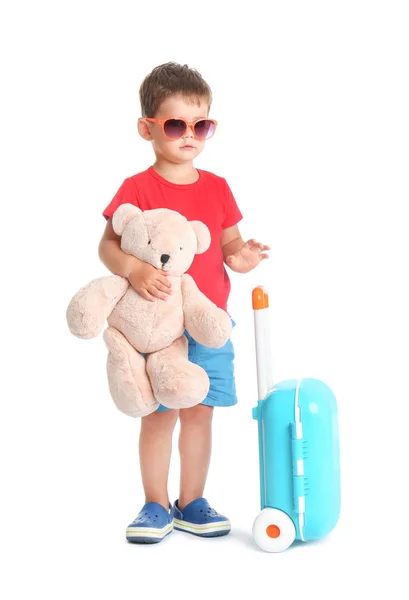 Menino bonito com brinquedo e mala azul no fundo branco — Fotografia de Stock