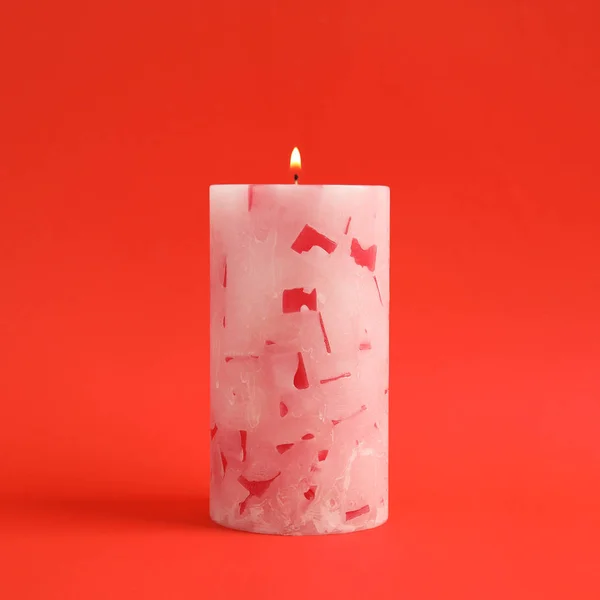 Alight scented wax candle on color background