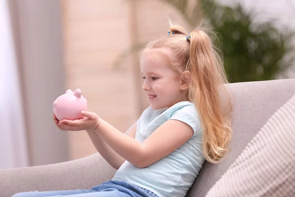 Klein meisje met Piggy Bank thuis — Stockfoto