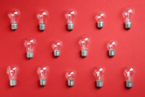 New incandescent lamp bulbs on red background, flat lay
